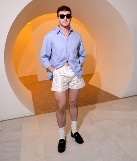 a man in a button down shirt light shorts and socks with loafers
