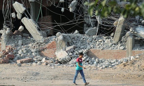 A boy passes demolished buildings in Saryaqos village, north of Cairo, Egypt,