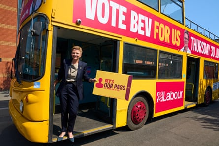 Bev Craig stands in the doorway of a bus with ‘Vote Bev for Us’ written on its side