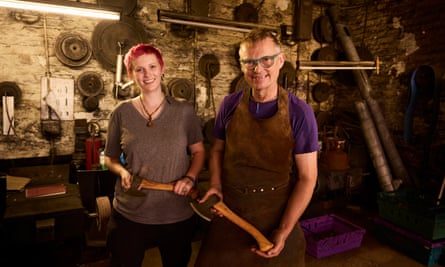 Robin and JoJo Wood stand holding axes in their workshop.