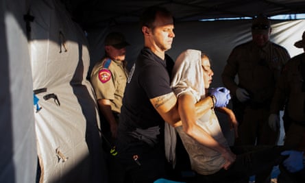 A firefighter lifts a migrant woman suffering from heat exhaustion on to a stretcher in the border community of Eagle Pass, Texas