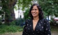 VV Ganeshananthan: she is pictured standing outdoors in a park with trees in the background; she is in her mid-40s and has shoulder-length dark, wavy hair; she wears a black dress with a lighter pattern plus a gold pendant necklace.