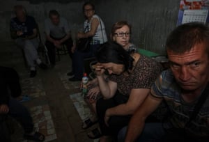 People look nervous as they take shelter in a basement where there is little light