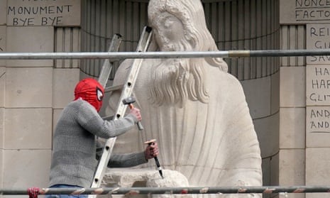 A man uses a hammer and chisel to damage the Prospero and Ariel statue by Eric Gill