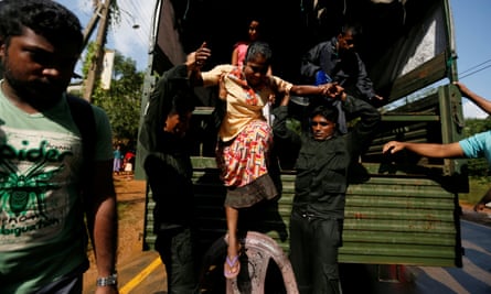 Sri Lankan army soldiers help a flood victim to get off from a truck during a rescue mission in Athwelthota village, in Kalutara.
