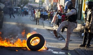 A police officer removes a tire set fire by supporters of presidential candidate Maryse Narcisse.