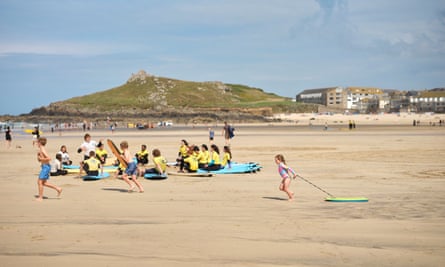 A surf school and children running on the beach in St Ives, Cornwall, UK, July 2024