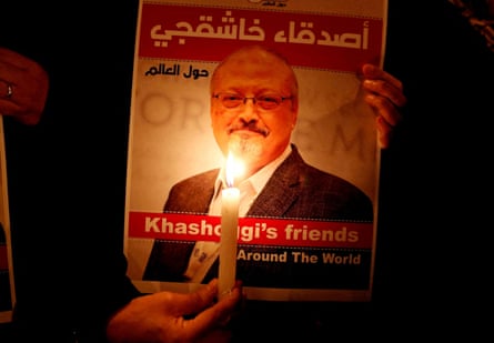 A demonstrator holds a candle next to a poster of Saudi journalist Jamal Khashoggi