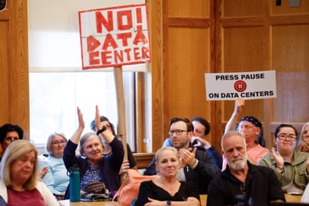 People applaud as others hold signs opposing datacenters