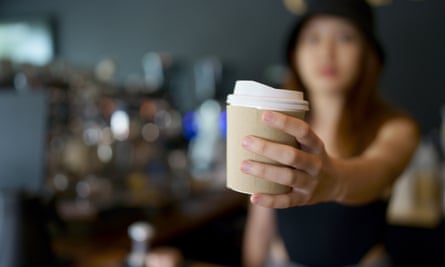 A woman holds a takeout coffee cup