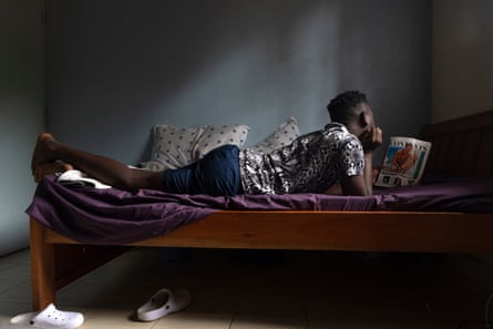 A man lies on a bed reading a magazine