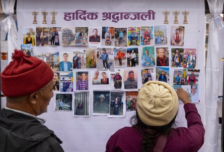 Two people study a wall of portrait photos