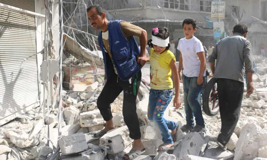 Injured Syrians walk through rubble