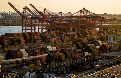 Large red cranes tower over stacks of shipping containers at the Port of Long Beach
