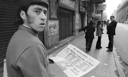 Black and white photo of a man looking over his shoulder, holding a newspaper announcing the military takeover and the death of Allende