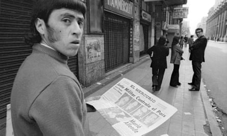 Black and white photo of a man looking over his shoulder, holding a newspaper announcing the military takeover and the death of Allende