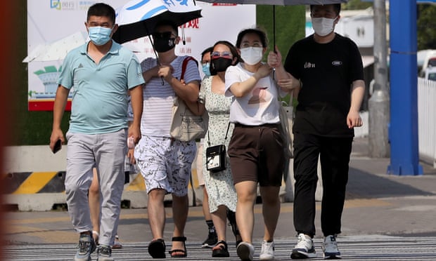 People walk on the street wearing masks and with umbrellas