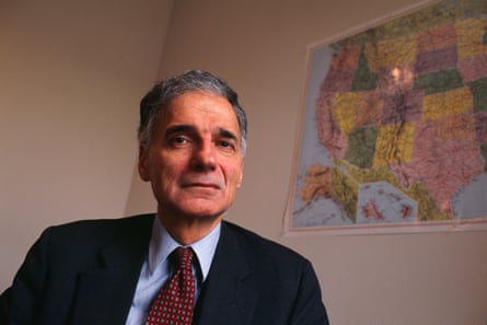 Man sits in a suit and red tie before a wall with a US map