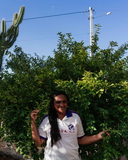 A woman poses in front of a bush