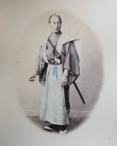 A man in traditional Japanese dress poses with two swords tucked into his sash