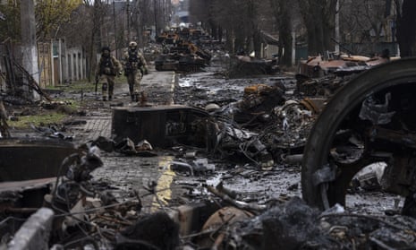 Soldiers walk amid destroyed Russian tanks