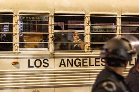 officers look to the side as a los angeles police bus holds people