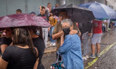 People stand with umbrellas in pouring rain.