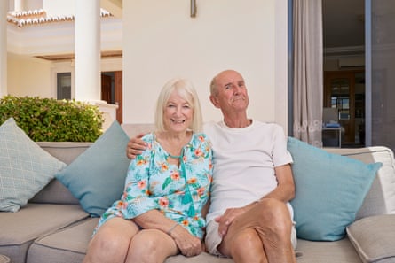 Abbot on an outdoor sofa with his arm around a smiling woman with a silvery bob and floral dress