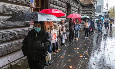 queue of people in winter jackets standing in the rain
