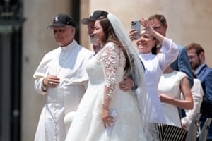 Pope Leo XIV wears a Chicago White Sox baseball cap as he poses for a photo next to a bride and groom