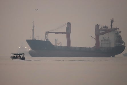 a motorboat passes an anchored cargo ship
