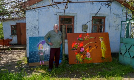 Dmytro Moldovanov posing with his paintings in front of his house in Parutyne, Mykolaiv.  