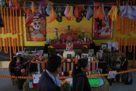 People walk past a Dia de los Muertos altar with a photo of Dolores Huerta and marigold decorations