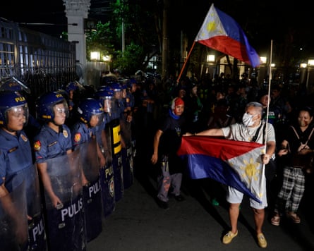 Police look on as a man holds out an upside down flag