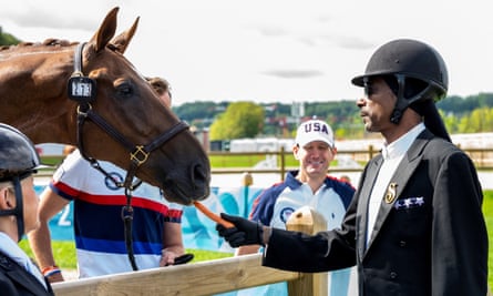 Snogg Dogg in dressage uniform feeding a carrot to a horse