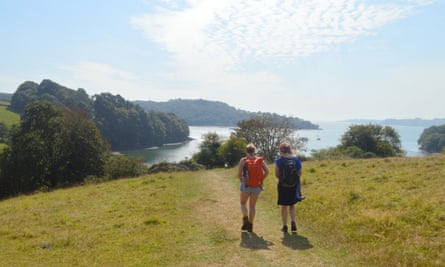 Two hikers in the countryside walk towards the water at Trelissick, Cornwall.