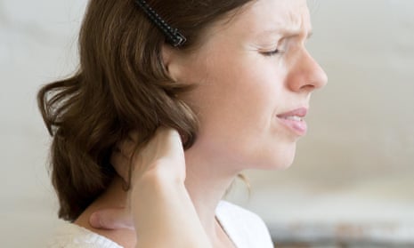 A woman sitting at a desk holding her head in pain