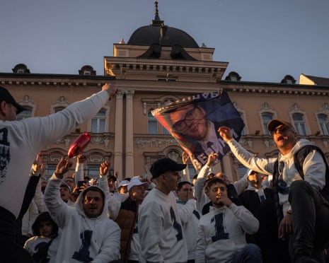 Supporters of Aleksandar Vucic raise fists and a flag at a pre-election rally