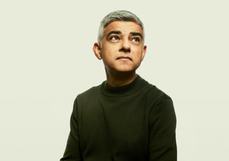 Head shot of London mayor Sadiq Khan looking up, against pale green background