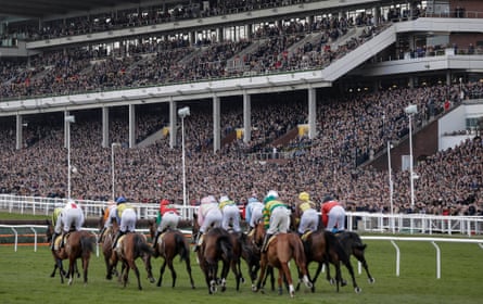 Runners in the opening race pass by the packed main stand during day four of the Cheltenham National Hunt Racing Festival at Cheltenham Racecourse on March 13th 2020 in Gloucestershire