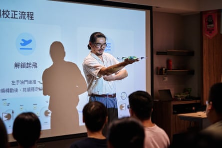 A man holds a drone in a classroom