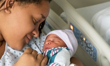 Black woman in a hospital bed holding her baby