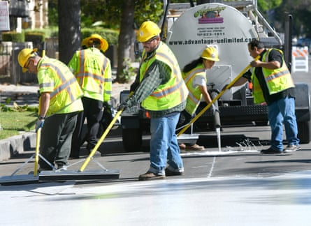 Workers apply a coating to a street.