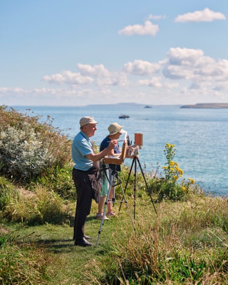 Two people painting on the clifftop above the sea in St Ives, Cornwall, UK, July 2024