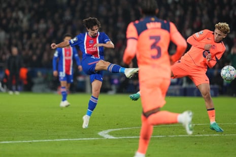 Vitinha of PSG kicks the ball mid-air as Barcelona defenders close in