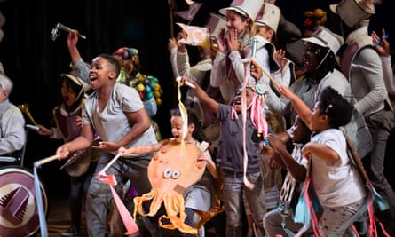 A large grouop of children and young people wave streamers and home-made art onstage