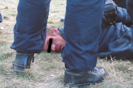 A man lies face down on the ground with his hands behind his back.