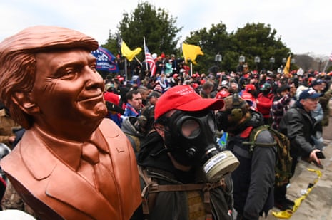 A supporter wears a gas mask and holds a bust of Donald Trump after he and hundreds of others stormed stormed the Capitol building in Washington on 6 January 2021