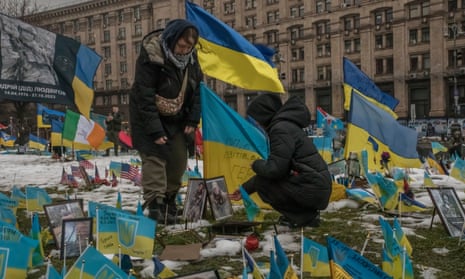 Two young women fix Ukrainian flags and pictures at the memorial in Maidan ruined by the intensity of the snow that has fallen in recent days.