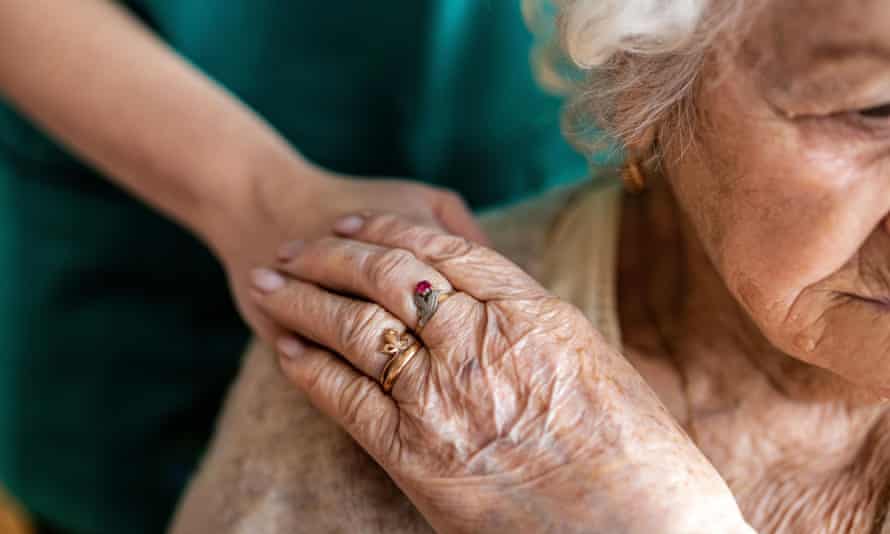 An older lady holding hands with a nurse.